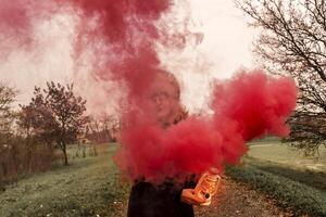 beautiful middle-aged woman on a country road showing a lantern that releases red smoke photo
