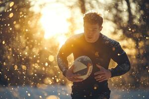 Rugby athlete jumping with ball, with evening sun rays and dust or snow in the background photo