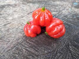 Tropical fruit. The Brazilian cherry or Pitanga also know as Eugenia uniflora, ripening on the pitangueira tree. Red fruit. photo