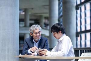 Portrait of Asian senior professor is giving advice to the college student on the research thesis while sitting in the university faculty for education, academic and business usage photo