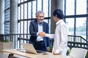 Senior asian executive manager is handshaking with the new trainee employee during probation to pass on knowledge and experience for new generation business inspiration, education and academic photo