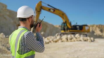 Engineer giving commands to employee in drilling machine using walkie talkie at quarry video