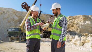 Two engineers geologists holds stone in hand and discussing quarry excavation plan video