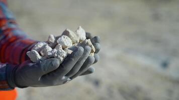 Worker engineer hold gravel in hand, checks quality at quarry, close up video