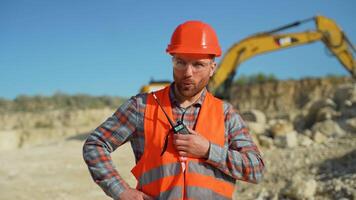 Foreman in uniform giving commands to employee in excavator using walkie talkie at construction site video