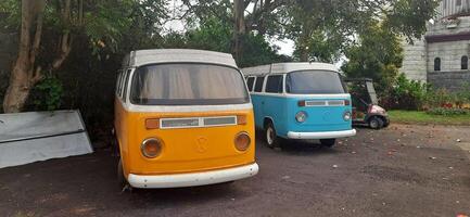 A blue and yellow minibus classic VolksWagen VW camper van parked in the street. Bandung, West Java, Indonesia - October 28 2024 photo