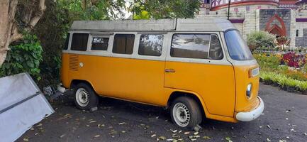 A yellow minibus classic VolksWagen VW camper van parked in the street. Bandung, West Java, Indonesia - October 28 2024 photo