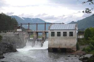 Hydroelectric power station against the backdrop of mountains, old dam photo