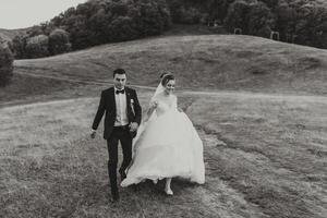 A bride and groom are running through a field photo