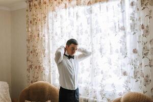 A man in a suit is standing in front of a window with floral curtains photo