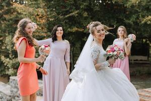 A bride is walking with her bridesmaids, all of them holding flowers photo