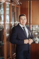A man in a suit and tie is standing in front of a cabinet photo