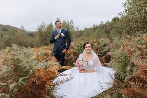 A bride and groom are posing for a picture in a field photo