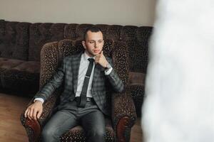 A man in a suit and tie is sitting in a chair photo