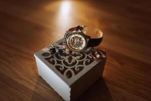 A watch is displayed in a box with a ring and cufflinks photo