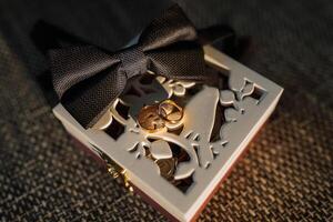 A box with a bow on it and two rings inside photo