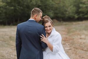 A bride and groom are posing for a picture in a field photo