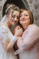 A bride and her mother are embracing each other photo