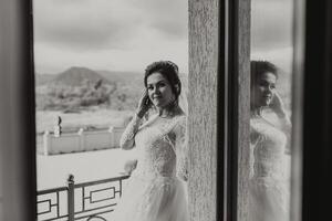 A woman in a wedding dress is standing in front of a window photo