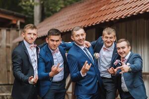 A group of five men in suits and ties pose for a picture photo