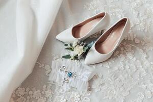 A pair of white shoes with a flower on them and a ring on the left foot photo