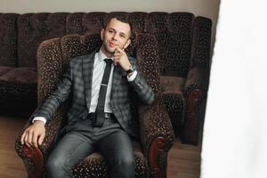 A man in a suit and tie is sitting in a chair photo