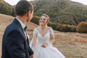 A bride and groom are standing in a field, smiling at the camera photo