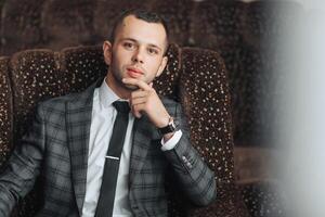 A man in a suit and tie is sitting in a chair photo
