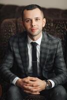 A man in a suit and tie sits on a couch photo