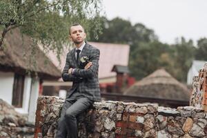 A man in a suit is sitting on a stone wall photo