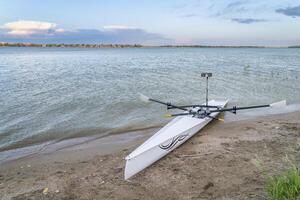 Loveland, CO, USA - June 2, 2024, Rowing shell by Liteboat on a beach at dusk, Boyd Lake State Park in spring scenery. photo