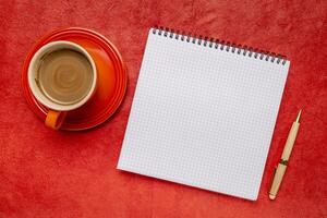 blank spiral notebook with ruled paper, flat lay with coffee on red textured art paper photo