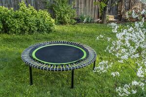 mini trampoline for fitness exercising and rebounding in a backyard, spring scenery with cherry tree in blossom photo