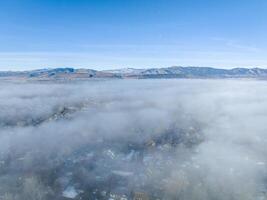 foggy winter morning over residential area of Fort Collins in northern Colorado after heavy rain and snow, aerial view with Front Range of Rocky Mountains in background photo