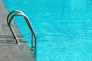 Serene pool with a stainless steel ladder invites relaxation at a summer resort photo