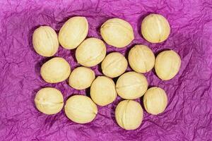 Whole walnuts arranged on crumpled purple paper photo
