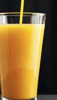 Close-up view of orange juice in a clear glass against a dark background video