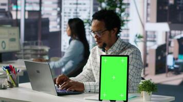 Corporate businessman reviewing data analytics next to mockup screen, doing report writing to ensure project progress. Multinational company worker managing financial planning. Camera A. video