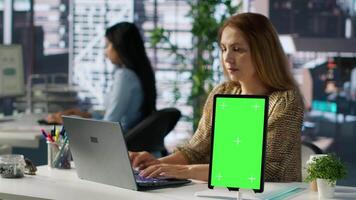 General manager reviewing a document with reports and isolated mockup, evaluating performance metrics to ensure company productivity. Uses her laptop to make informed decisions. Camera A. video