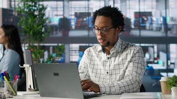Account executive multitasking on his computer to finish business tasks and operations. African american man reviewing financial documents for company success, productivity. Camera A. video