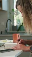 Person is sketching in notebook while working remotely at desk with laptop. Freelance work at home office. Graphic designer drawing sketch video