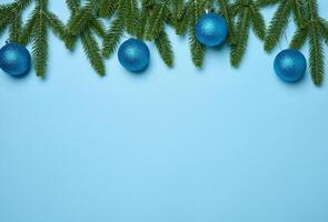 Shiny blue balls and green fir branches on green background, Christmas background. photo