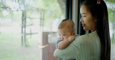 Portrait of Beautiful woman stands in a coffee shop, smiling warmly as she gently cradles a baby boy in her arms. Relaxed atmosphere add to the heartwarming moment. photo