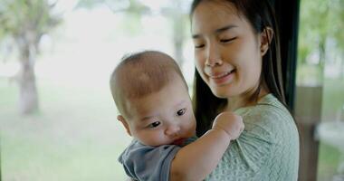 Portrait of Beautiful woman stands in a coffee shop, smiling warmly as she gently cradles a baby boy in her arms. Relaxed atmosphere add to the heartwarming moment. photo