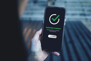 Smartphone screen shows Registration completed with Log in to proceed to the next step. The technological concept of project registration or membership application. photo