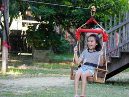 Kids play outdoors on a playground with modern slides, rope net bridges, climbing swings, climbers in summer. photo