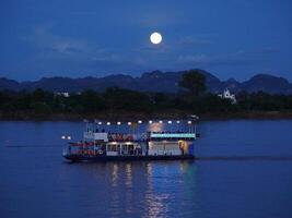 A cruise ship takes tourists on a night tour of the Mekong River on a full moon night. photo
