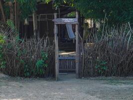 Rustic fence made with tree branches and wooden posts with a small gate leading to the entrance to a mini zoo. photo