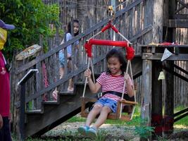 Kids play outdoors on a playground with modern slides, rope net bridges, climbing swings, climbers in summer. photo