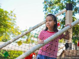 Kids play outdoors on a playground with modern slides, rope net bridges, climbing swings, climbers in summer. photo